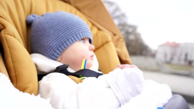 Little Ukrainian girl on the street with yellow-blue ribbons, Ukrainian flag