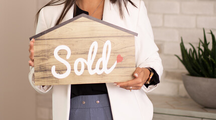 person holding a sold sign in the shape of a house real-estate agent   - obrazy, fototapety, plakaty