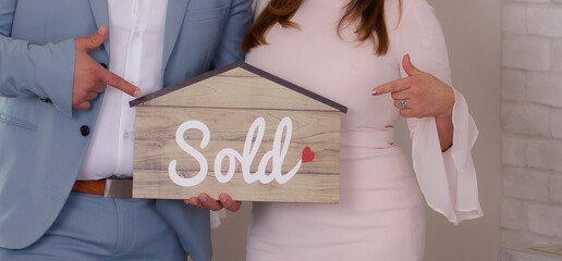 person holding a sold sign in the shape of a house real-estate agent   - obrazy, fototapety, plakaty