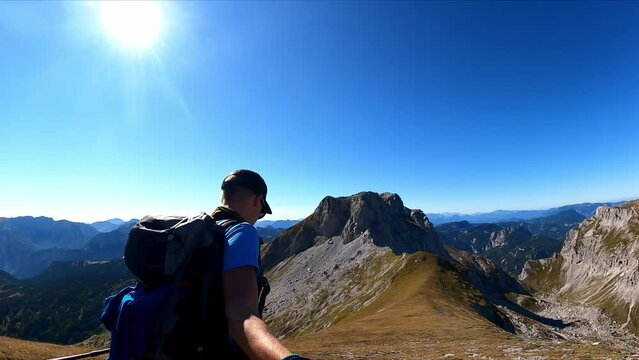 Man with backpack filming himself while hiking to the summit of Hinterer Polster in the scenic region of the Hochschwab mountain in Styria, Austria. Alpine meadows and sharp rocks. Hike concept. Free
