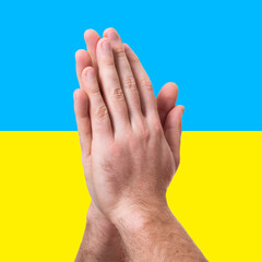 Pray for Ukraine. Male hands folded in a prayer pose asking for help over Ukrainian yellow-blue flag. Stop war in Ukraine!