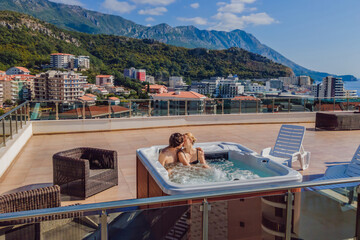 Drone view. Portrait of young carefree happy smiling couple relaxing at hot tub during enjoying happy traveling moment vacation life against the background of green big mountains