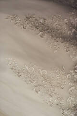 Close-up shiny symbolic flowers pattern on classical white wedding dress