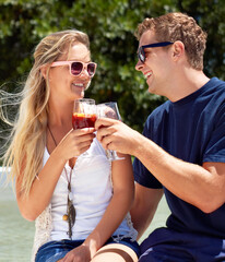To us. A young couple toast each other on a summers day.