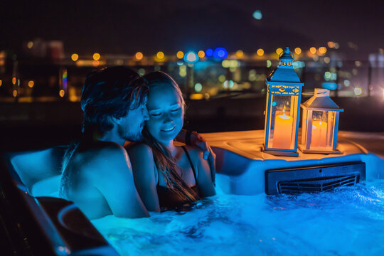 Portrait of young carefree happy smiling couple relaxing at hot tub during enjoying happy traveling moment vacation life against the background of green big mountains at night