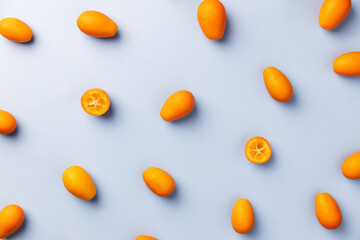 Fototapeta na wymiar Light blue flat lay with top view on fresh ripe orange cumquat or kumquat citrus. Full, cut and sliced fruits. High quality pattern photo. Healthy eating concept. Vegan or vegetarian eating food