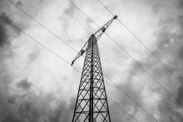 Bottom up view of an electricity pylon with high voltage power lines in black and white