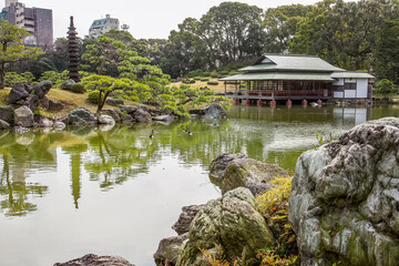 Pagoda on island and small pines on it   and teahouse on the shore of lake in the Kiyosumi Teien in Tokyo