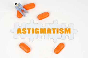 On the white surface of the tablet, a miniature human figure and puzzles with the inscription - ASTIGMATISM