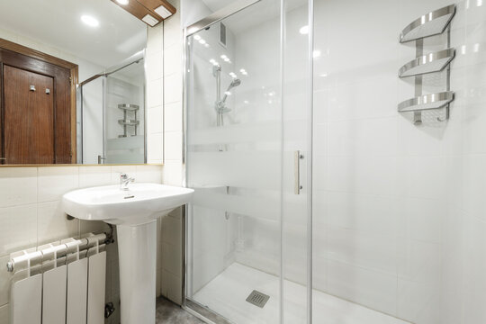 Toilet with glass shower stall, white porcelain sink in vacation rental apartment