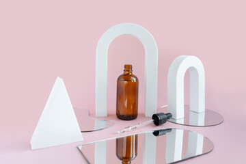 A dark bottle with a pipette on a pink background with geometric shapes and a mirror. Cosmetic composition for skin care. Cosmetics packaging template with your design.