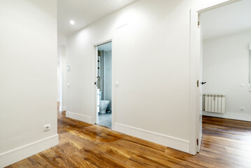 Distributor of a residential house with access to an empty room, a bathroom and a corridor with hardwood floors