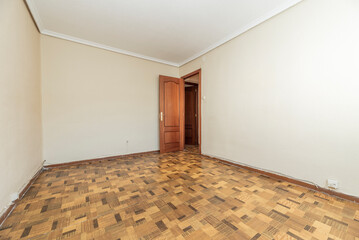 Empty living room with ugly brown sunscreen floor, dark wood door and plaster molding on the ceiling