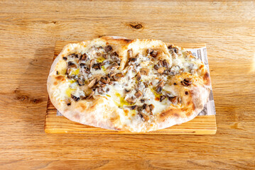 Pizza with mushrooms, mozzarella cheese, olive oil and thin wheat dough cooked in a stone oven