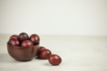 Dark rustic eggs in deep dark dish on a white background