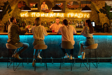 Friends talking with bartender in bar