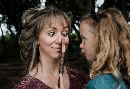 daughter playing funny faces with sticks with mother cross eyed