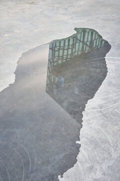 Building reflecting in puddle in city