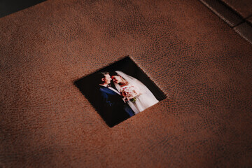 cover of wedding photobook in brown leather binding with photos