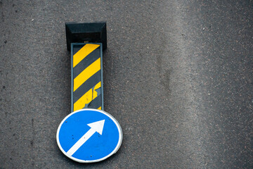 A road sign indicating the separation of traffic flows is installed on the carriageway in front of a dangerous section of road. A strong wind knocked over a road sign. - obrazy, fototapety, plakaty