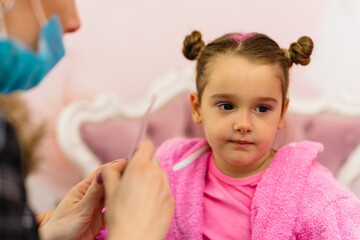 Little girl having a makeup treatment in children's spa center.