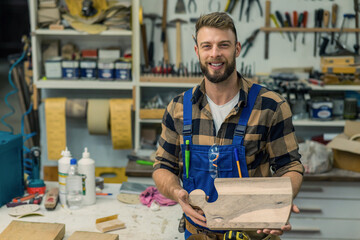 Handsome young carpenter smiles and showing his last project