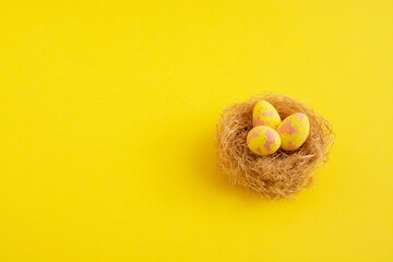Yellow pastel easter eggs in nests on a sunny background. Minimal creative concept of Easter.