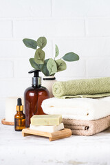 Spa background in white spa salon or bathroom. Stack of towels, shampoo bottle, serum and other cosmetics.
