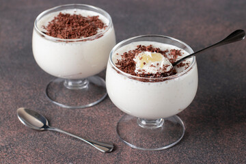 Pudding jelly of cream or milk with pinepple, sprinkled with chocolate chips in two cups on brown background, Dessert blancmange