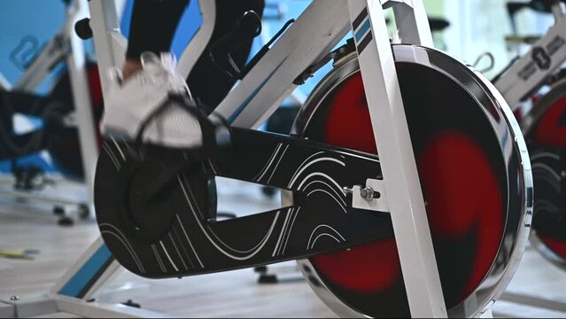 Athletic young adult caucasian woman exercising on a cycling machine in a sports club. Cardio training concept.