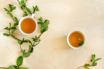 Healthy mint tea and mint branches on a wooden table, top view. Selective focus with copy space. Daylight