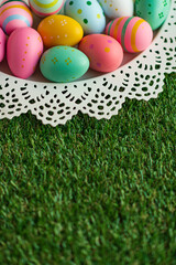 Vertical Easter background with colorful painted Easter eggs and green grass. Top view with copy space. Easter holidays banner and header.
