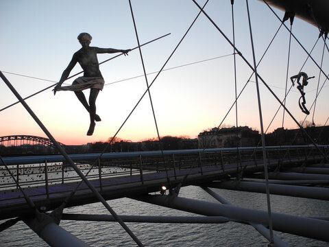Krakow, Poland - March 10, 2022: evening view to Vistula (Wisla) river and Father Bernatek's Bridge with balancing figures of gymnasts by polish sculptor Jerzy Kedziora 