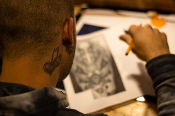 Portrait of a master calligrapher. A tattoo artist makes a sketch while sitting at a table in the...
