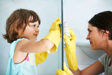 Scrub till it shines. Shot of a mother and daughter doing chores together at home.