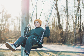 Girl with yellow cap playing on the swing