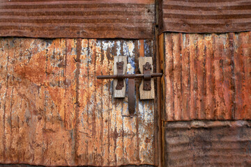 door made of rusted sheet steel plates, with a closed latch in its central part, corrosion