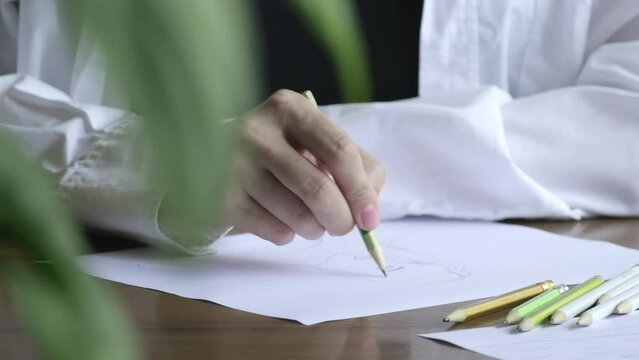 Painter paints picture portrait of beautiful woman or self-portrait. Close up of female hands of an artist or Illustrator drawing pencil sketches on white paper. Concept of hobby and lifestyle
