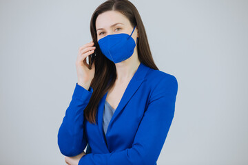 Young woman wears a ffp2 protective mask and speaks on the phone . Work in the office with ffp2...