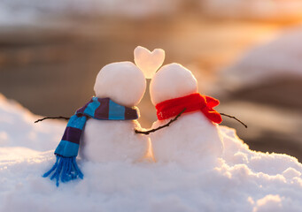 Cute snowman couple in love with snow heart between them.