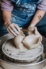 Young beautiful woman in blue apron creating handmade ceramic bowl in a pottery. Creative workshop.