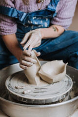 Woman hands working on pottery wheel and making a pot.