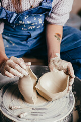 Woman hands working on pottery wheel and making a pot.
