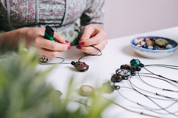 Woman hands making handmade gemstone jewellery, home workshop. Women artisan creates jewellery. Art, hobby, handcraft concept