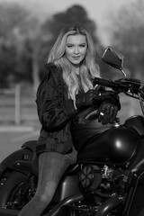 Fototapeta na wymiar A Lovely Blonde Model Enjoys The Outdoor Weather While Posing With Her Motorcycle