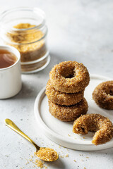 Delicious sugar coated donuts on a plate on white textured background with tea and sugar