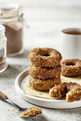 Delicious stack of sugar coated donuts on a plate on white textured background close up with tea and sugar