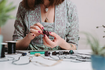Woman hands making handmade gemstone jewellery, home workshop. Women artisan creates jewellery....