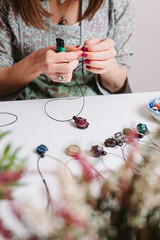 Woman hands making handmade gemstone jewellery, home workshop. Women artisan creates jewellery. Art, hobby, handcraft concept