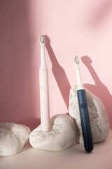 New modern ultrasonic toothbrushes. Dental care supplies with white stones on pink pastel background. Oral hygiene, dental health, healthy teeth. Dental products Ultrasonic vibration toothbrush.